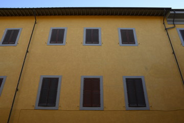 Obraz premium Facciata palazzo giallo con finestre e persiane