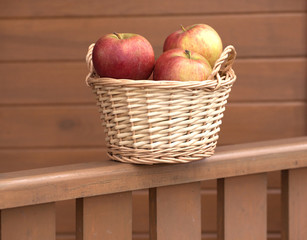 Ripe red and yellow apples in light brown wicker basket closeup