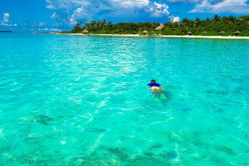 Fototapeta na wymiar Young man snorkeling in clear tropical turquoise waters