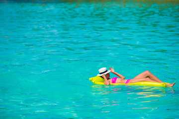 Woman relaxing on inflatable air mattress at turquoise water