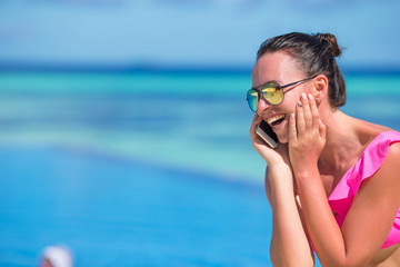 Young beautiful woman talking by phone on white beach