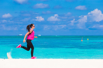 Fit young woman running along the tropical beach in her
