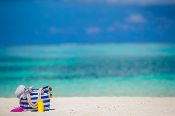 Blue bag, straw white hat, flip flop and sunscreen bottle on