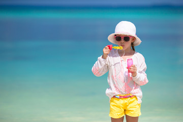 Adorable little girl blowing soap bubbles on the beach