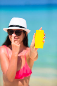 Young Happy Woman Applying Suntan Lotion On Her Nose On White