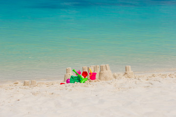Sandcastle at white beach with plastic kids toys background the