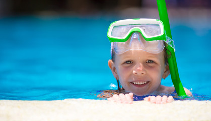 Adorable little girl at mask and goggles in outdoor swimming