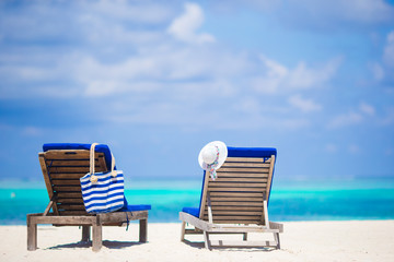 Lounge chairs with bag and hat on tropical beach at Maldives