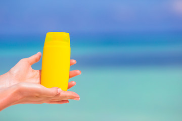Female hands with suncream bottle background blue sea