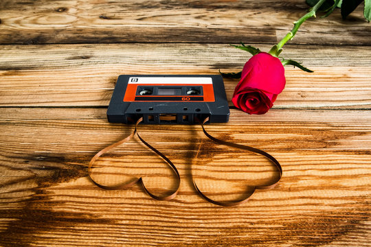 rose and vintage audio cassette with loose tape shaping two hear