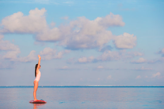 Beautiful young woman surfing on stand up paddle board at exotic