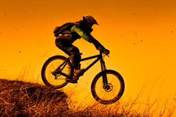 Fototapeta na wymiar Downhill mountain bike ride at sunset