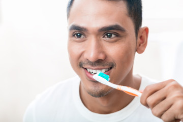 Asian man brushing teeth