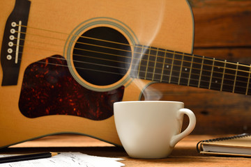 Cup of coffee with smoke and guitar on wooden table