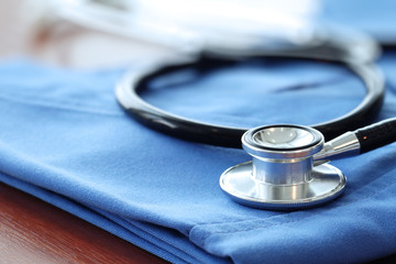 Stethoscope with blue doctor coat on wooden table with shallow D