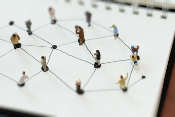 close up of miniature people with social network diagram on open