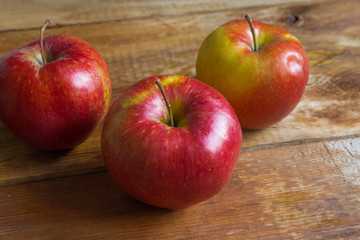 three red ripe apples on a wooden table