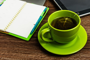 Office desk with laptop computer, planner, cup of tea