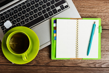 Office desk with laptop computer, planner, cup of tea