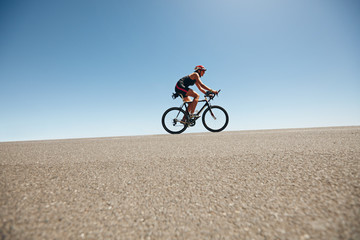 Fototapeta premium Female cyclist on a country road training for triathlon