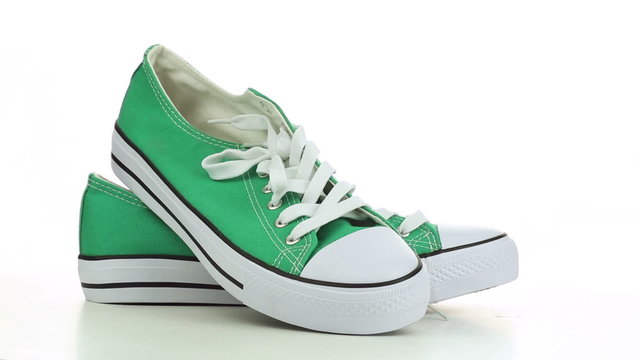 Green sneakers revolve on a white background