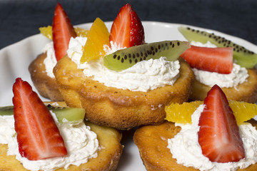 Cupcakes with whipped cream, strawberries, orange and kiwi