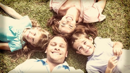 Happy family lying on the grass in a circle
