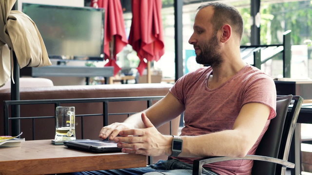 Man finishing working on laptop, relaxing and drinking beer 