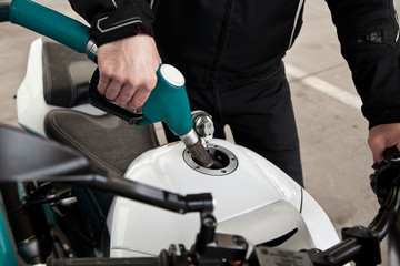 hand fuel nozzle in pouring to motorcycle at gas station