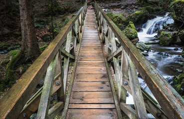 wooden foot bridge over waterfall