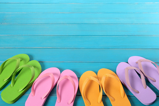 Beach background border summer vacation holiday with line row of flip flop sandals on old blue wood planked decking space for copy text photo