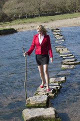 Stepping stones woman crossing river with a stick