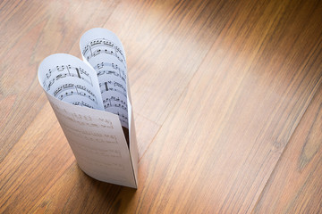 Paper sheet making heart shape on wood background