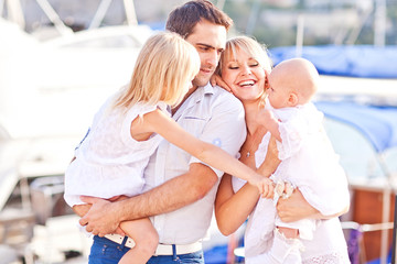 Obraz premium Happy family having fun walking on the mooring near yachts