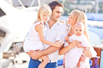 Obraz premium Happy family having fun walking on the mooring near yachts