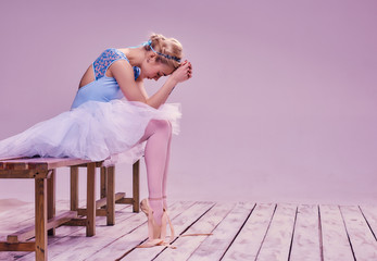 Tired ballet dancer sitting on the wooden floor - Powered by Adobe