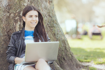 Young woman using computer at park in London