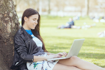Young woman using computer at park in London