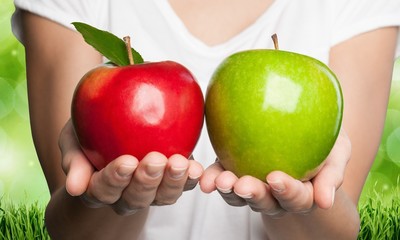 Comparison. Hands holding red and green apples