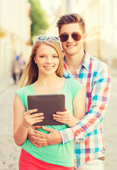 smiling couple with tablet pc in city