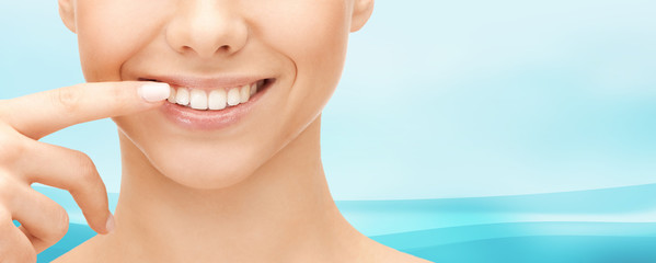 close up of smiling woman face pointing to teeth