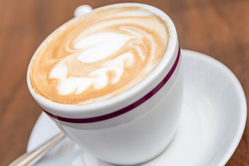 White Cup Of Coffee With Heart Pattern On Wooden Table