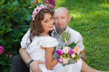 Beautiful couple with a wedding bouquet of flowers sitting 