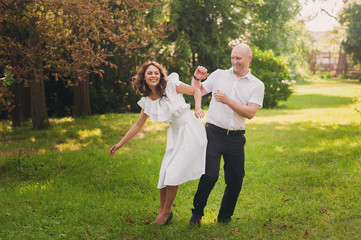 Naklejka na ściany i meble Beautiful young couple dancing and having fun around on grass