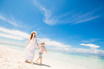 Happy beautiful young mother and son enjoying beach time with