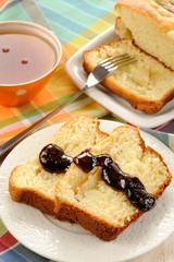 Mascarpone cake slice, cup of tea in orange teacup, blueberry ja