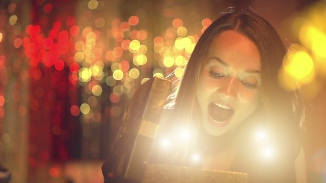 Beauty girl opens Christmas gift box with miracle gift