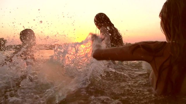 Group of happy teen girls playing in water at the beach