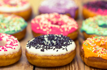 Colorful glazed donuts on the wooden table