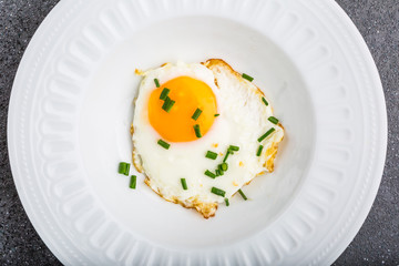 Fried egg with chives on white plate